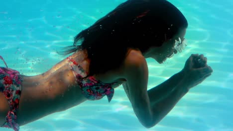 Brunette-swimming-underwater-in-the-pool