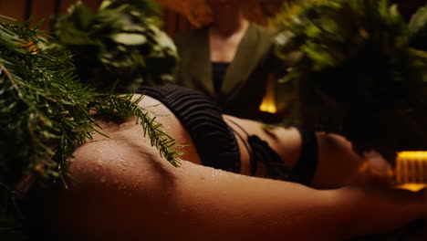woman in a sauna with herbal branches