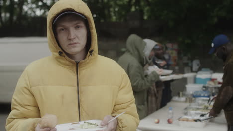 young man receiving food at an outdoor charity event