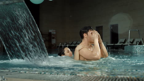 cute couple piggyback riding in pool. romantic man and woman hugging in spa