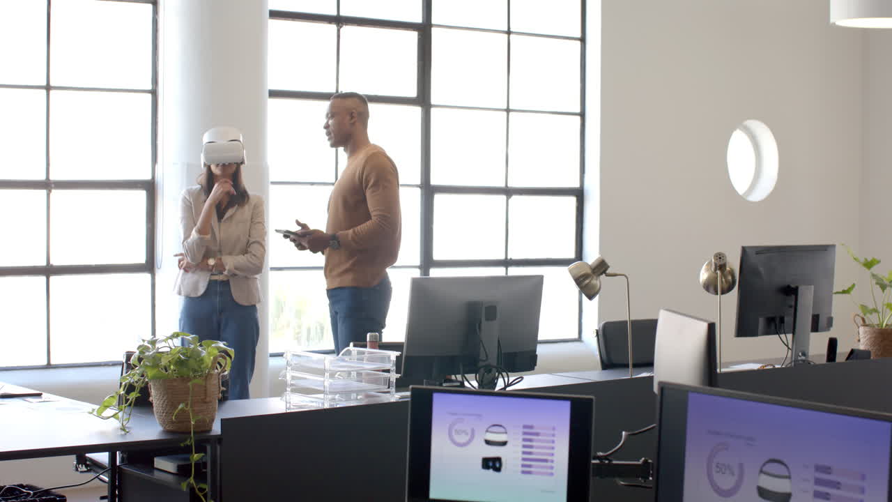 Using VR headset, woman discussing project with colleague in modern office