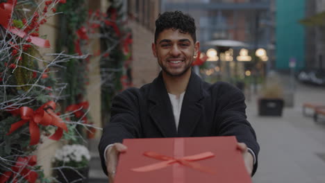 man offering a red gift box during the holidays