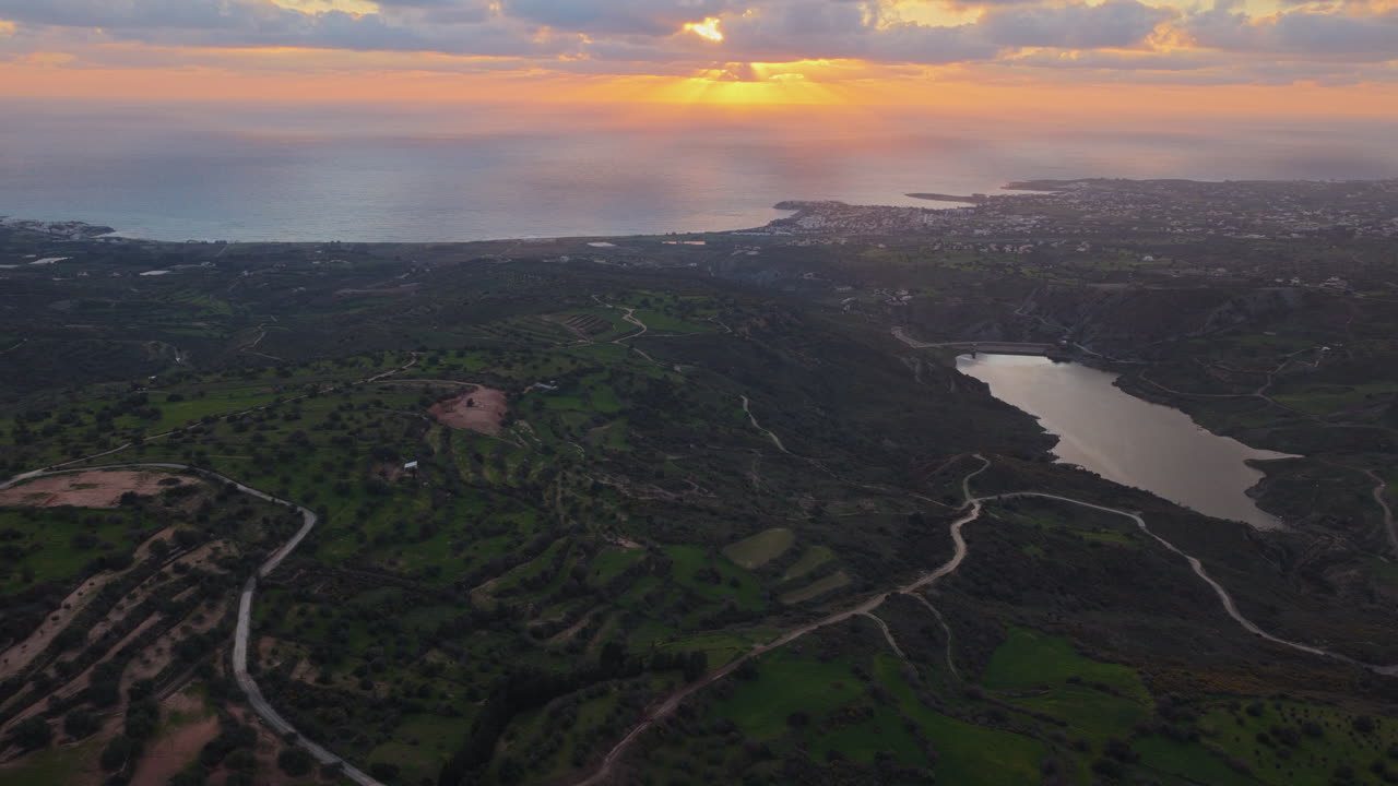 Vista aerea con drone di colline verdi e costa durante il tramonto a Cipro.