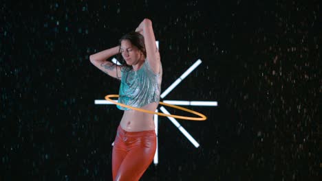 beautiful female hula hooper elegantly dancing with hula hoop in wet studio slow motion