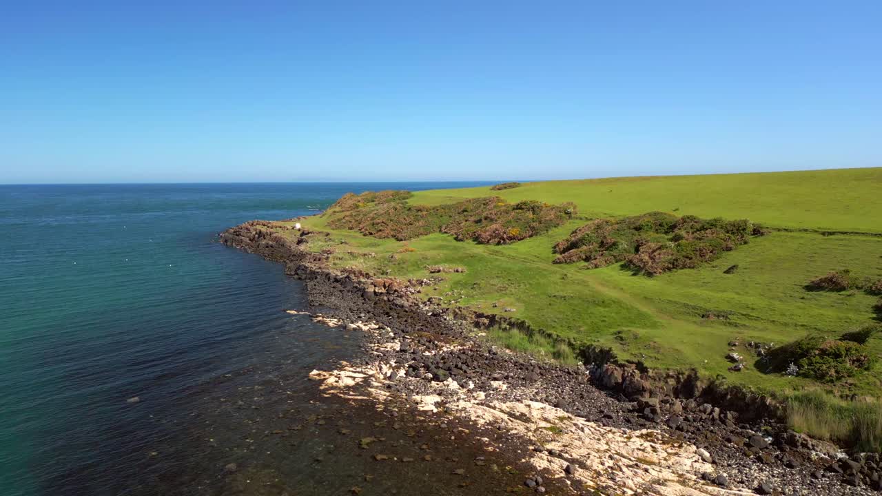 Advancing and rising aerial video of the coastline at Brown's Bay, in County Antrim, Northern Ireland, UK on a bright and sunny day. Filmed in 4K, 60FPS and with Rec709 color.
