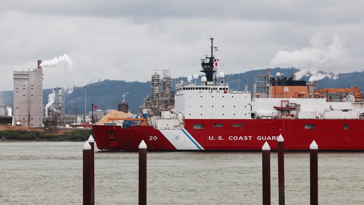 Large vessel and tugboat on river with industrial Longview, USA background.