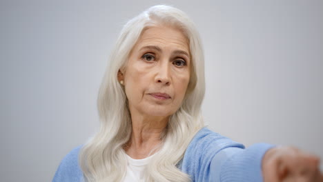 Mature-woman-pointing-to-camera-indoors.-Serious-lady-looking-strict-in-studio.