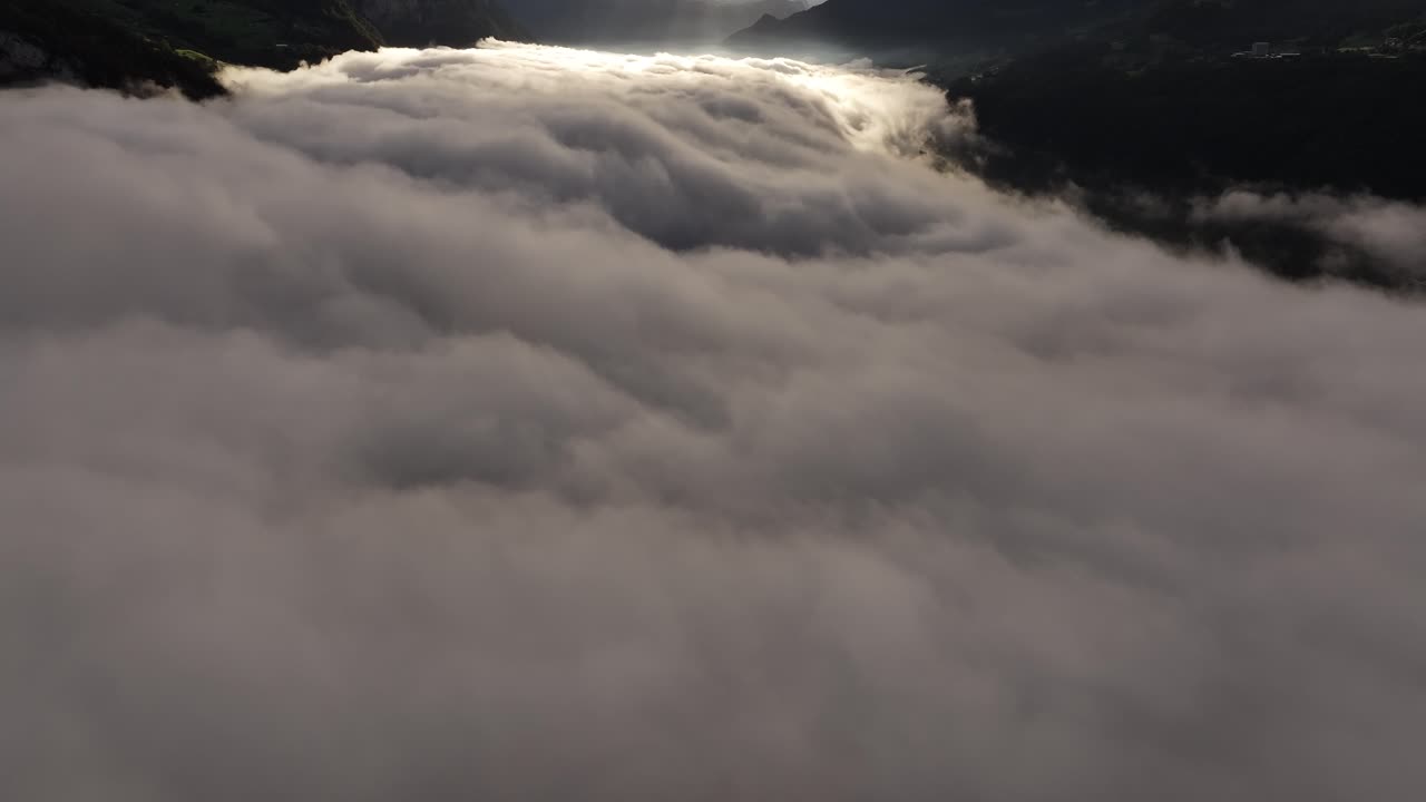 Drone flight emerging from the clouds to reveal the breathtaking Swiss Alps.