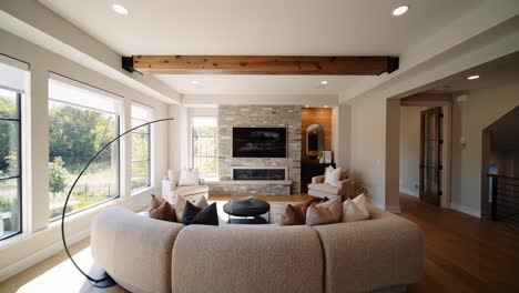 a modern living room with a stone fireplace, large windows, and cozy seating, filled with natural light