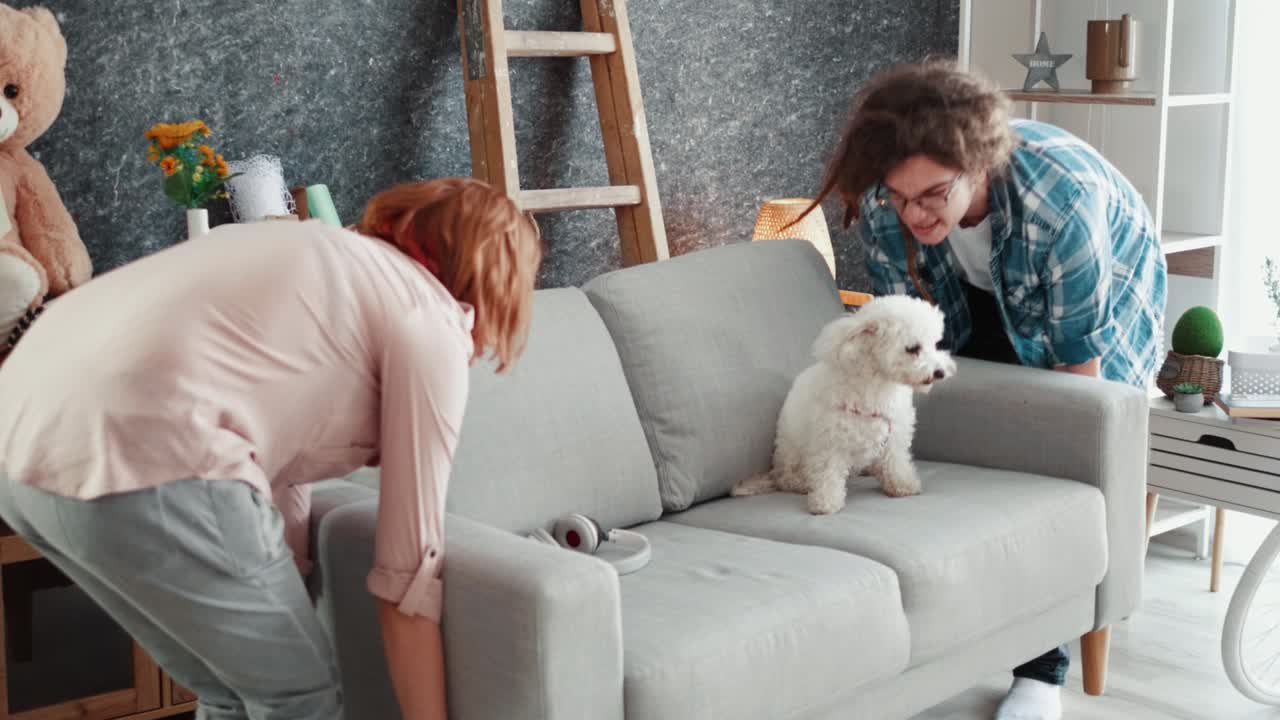 Happy couple moves into a new home carrying a new couch on which their pet is housed