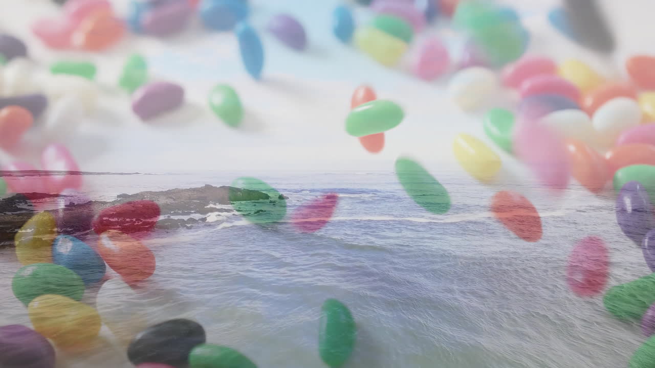 Floating colorful jelly beans over ocean waves and rocky shoreline animation