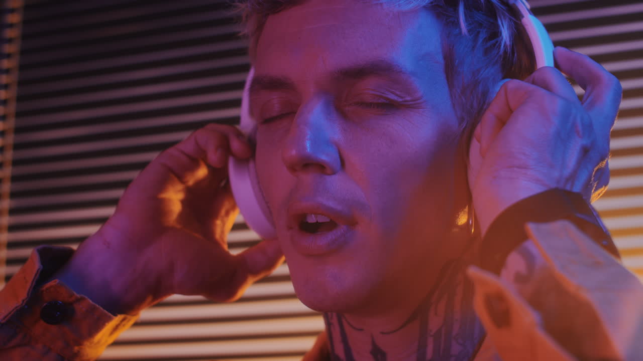 Man with Tattoo on Neck Listening to Music in Headphones