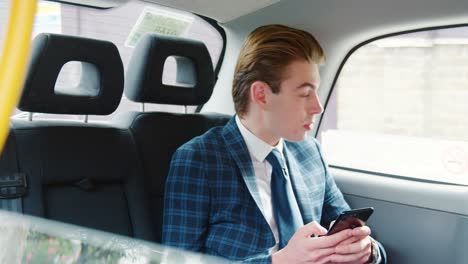 stylish man wearing suit using mobile phone in taxi cab