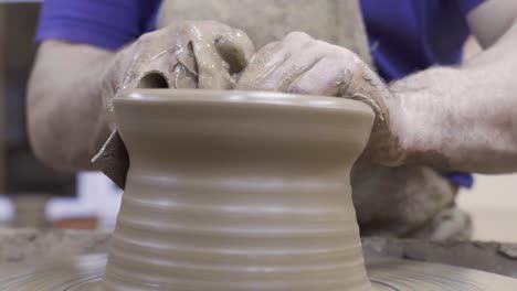 person shaping clay on a pottery wheel