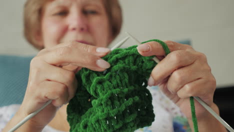 senior woman knitting a green blanket