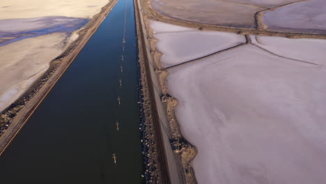 pink salt flats next to canal and train tracks, utah, aerial view