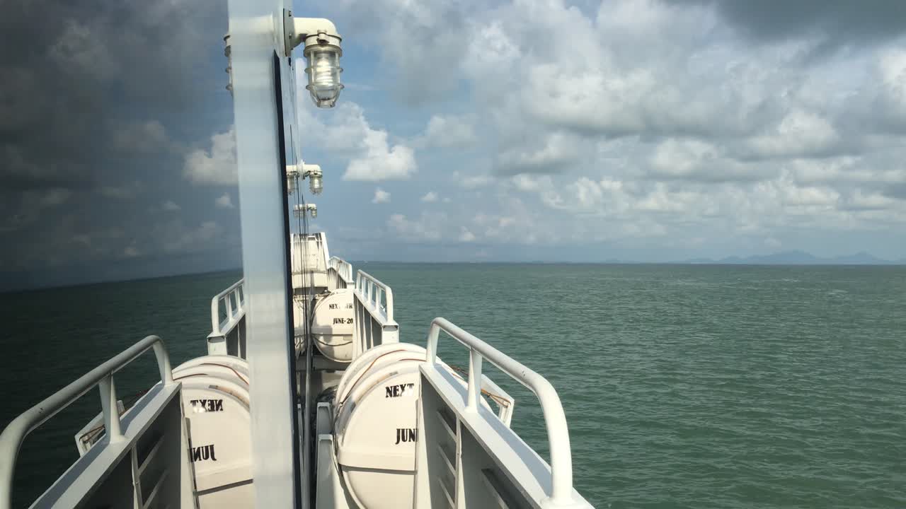 Blickwinkel von einem fahrenden Boot mit sichtbarem Deck und Fensterreflexion, der auf den Meereshorizont in Südostasien gerichtet ist.