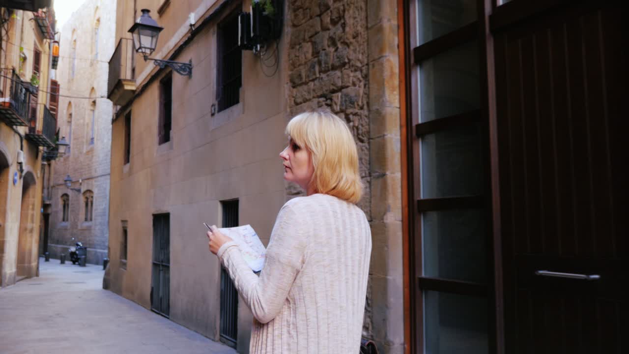 Una donna con una mappa in mano cammina per le stradine del quartiere Gotico a Barcellona 2