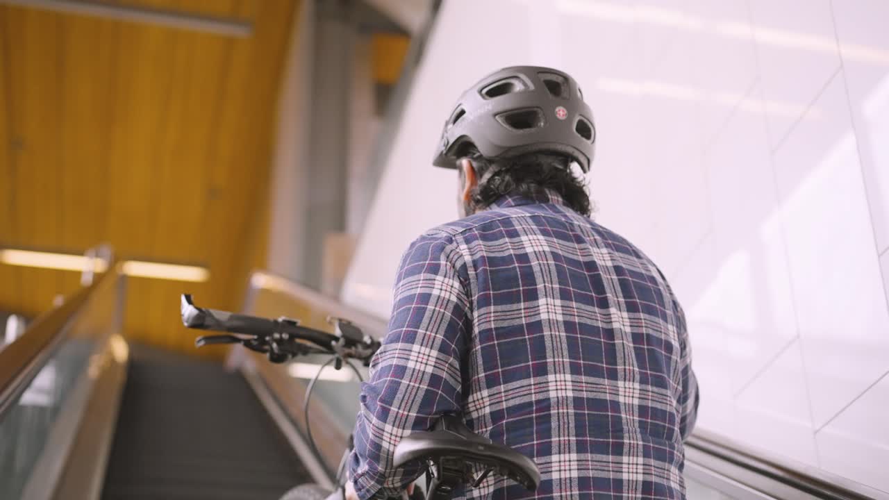 A man rides on the escalator while carrying his bike to board a train.