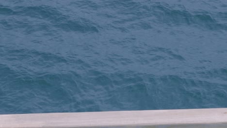 looking down at calm blue sea waves view from side of ferry boat