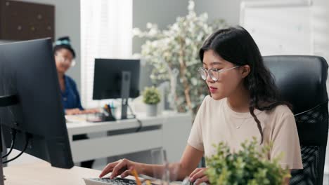 busy afternoon at the office, two elegant women work in front of the company's computers, clicking fingers on the keyboard, talking among themselves, joking, caring about collaborative relationships