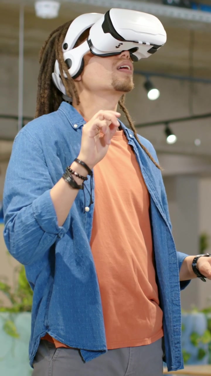 Video verticale: Uomo in camicia blu che alza la mano con le cuffie durante una demo, pizzicando per selezionare