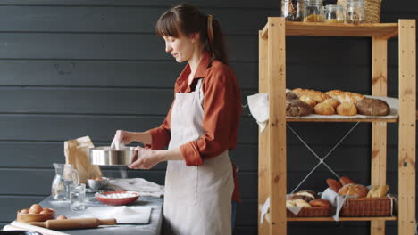 Chef-De-Panadería-Femenina-Tamizando-La-Harina-En-La-Cocina