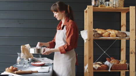 female bakery chef sifting flour in kitchen