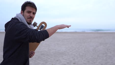 surfer with longboard pointing to the sea and drawing waves with his hand