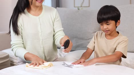 a mother and son clean a desk together, sharing smiles and teamwork in a bright, cozy room