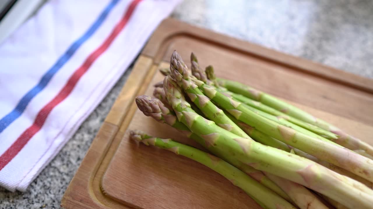 Pousses d'asperges sur planche en bois dans une cuisine