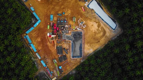 Cinematic-4K-Drone-Footage-of-Onshore-Drilling-Rig-equipment-structure-for-oil-exploration-and-exploitation-in-the-middle-of-jungle-surrounded-by-palm-oil-trees-during-sunset-and-high-oil-price