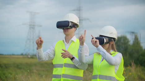 two engineers of power engineers in vr glasses move their hands simulating the operation of the interface of the control system and planning of high-voltage lines for the delivery of electricity from alternative energy sources.