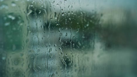 falling drops on glass. wet window on blur background. rain drops running down the window surface.
