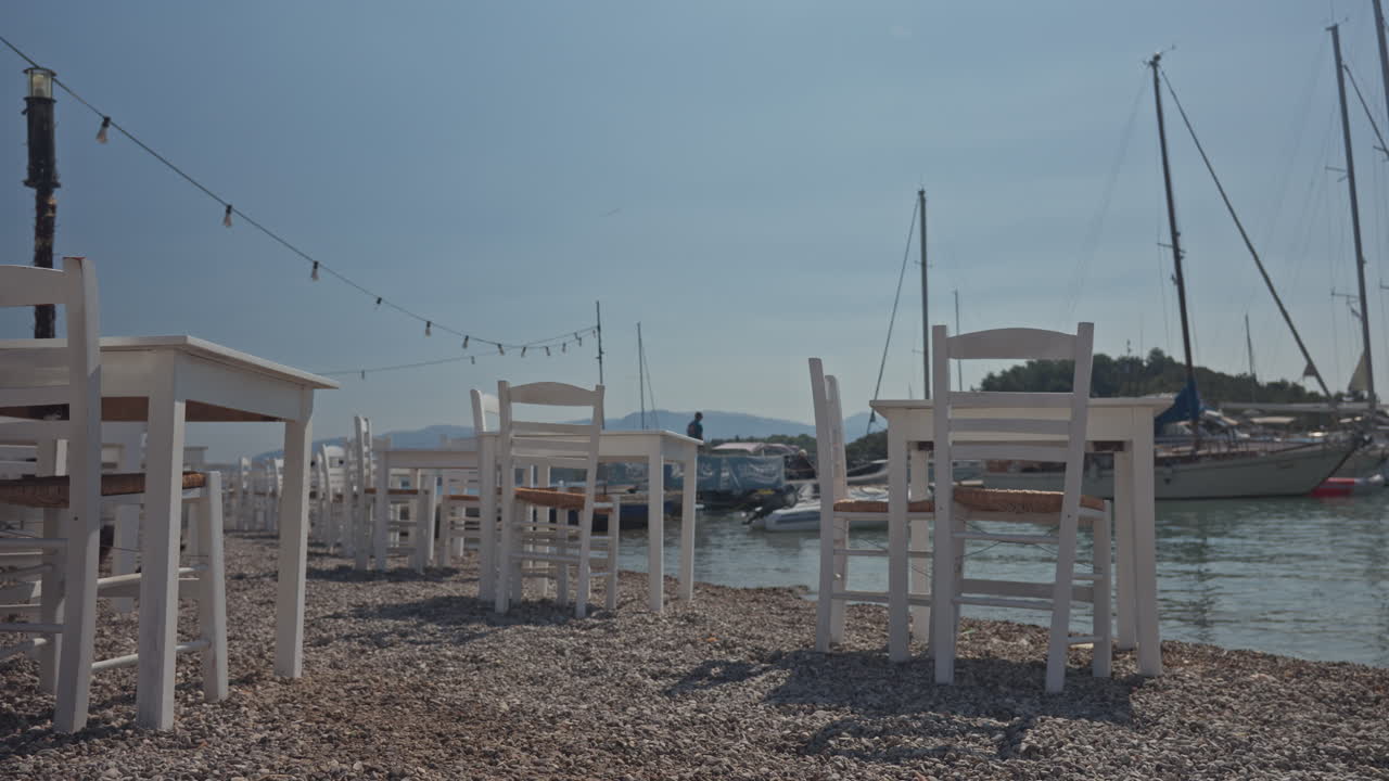 tables and chairs in a terrace bar by the harbour in nydri lefkada, greece