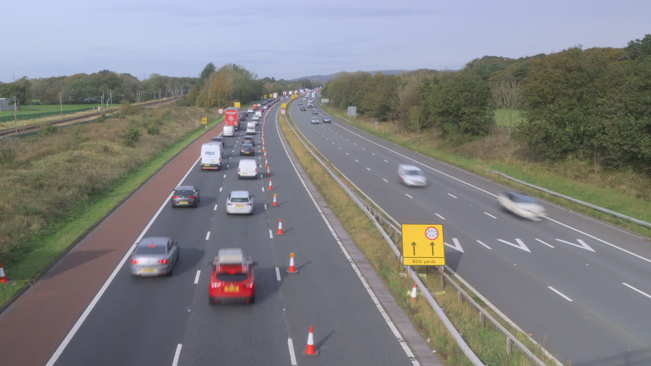 왼쪽으로 지나가는 열차와 함께 영국 고속도로에서 느리게 움직이는 교통