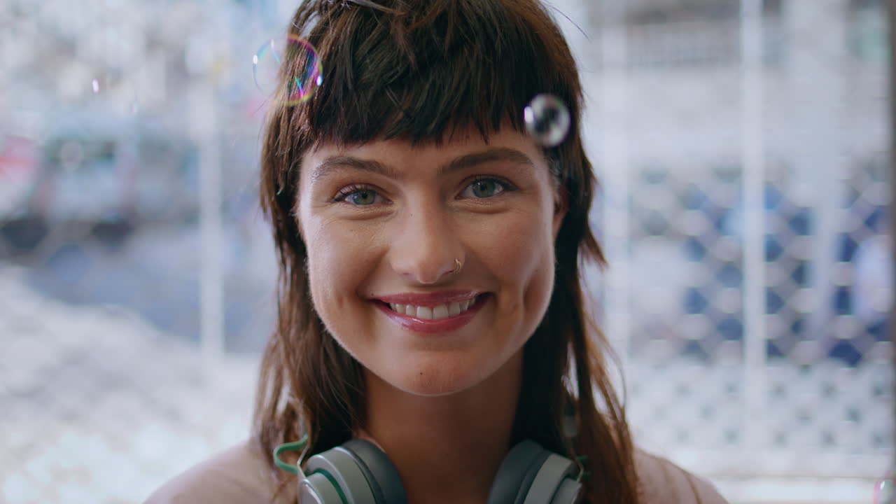 Primo piano di una ragazza hipster che posa tra bolle di sapone nell'aria. Adolescente sorridente con stile.