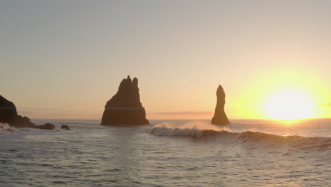 Low-aerial-shot-over-waves-towards-Reynisdrangar-Sea-stacks-Iceland