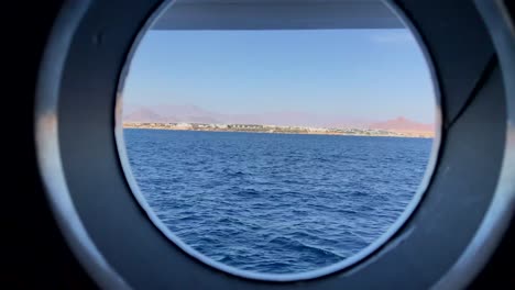 view from the window of a cruise ship porthole showing the mountains of egypt at sunset