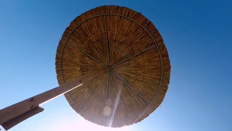 la parte inferior de una sombrilla de mimbre en un día soleado.