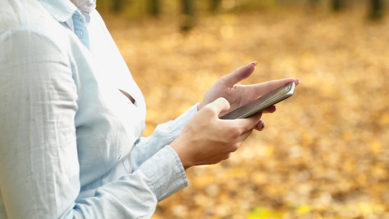 Girl with phone in park. Young woman speaking on mobile phone in park