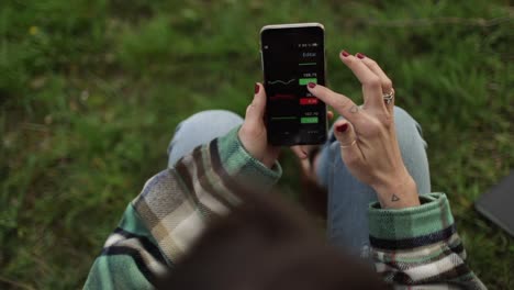 Crop-broker-using-trading-app-on-smartphone-on-lawn