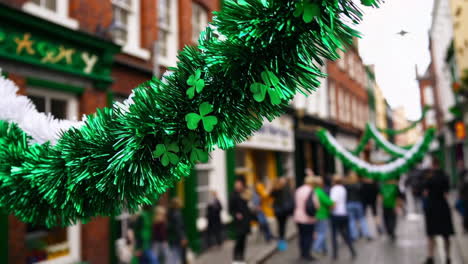 green tinsel garlands and shamrocks decorate a city street for st. patrick's day