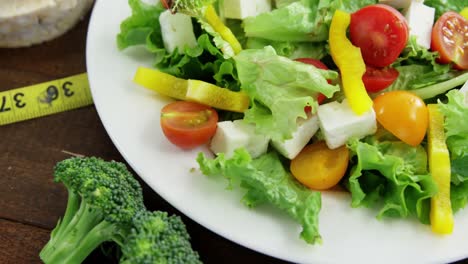 Vegetable-salad-with-granola-bar-and-measurement-tape