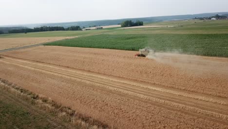 Eine-Filmische-4K-Drohnenaufnahme-Eines-Mähdreschers-Bei-Der-Ernte-Eines-Feldes-In-Frankreich,-Die-Die-Landwirtschaft-Mit-Epischer-Aussicht-Und-Dramatischem-Staub-Zeigt