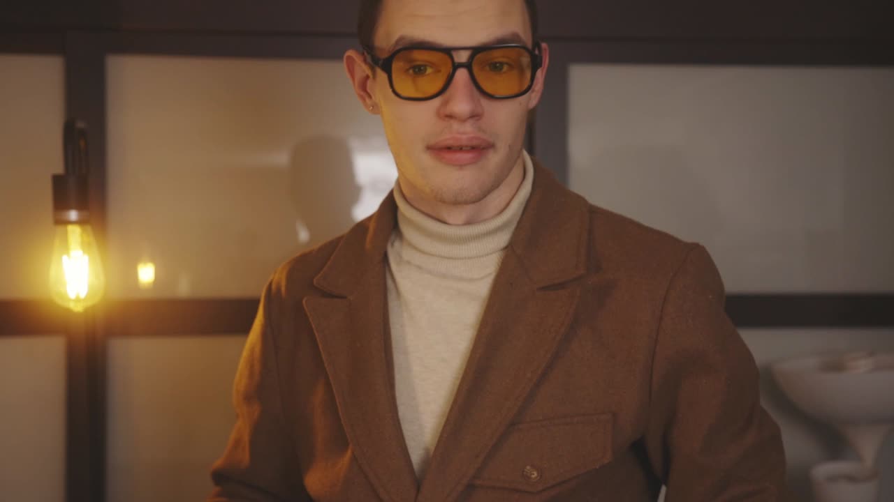 편광 선글라스를 쓴 세련된 남자는 집에 갈색 블레이저를 입는다