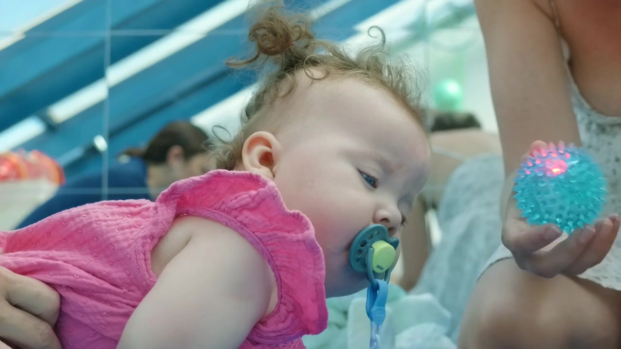 An adult helps a baby girl clap her hands together during play
