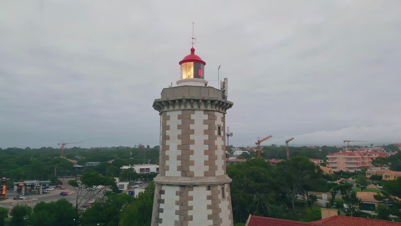 Lighthouse tower shining shore under gloomy cloudy sky aerial view. Beacon light