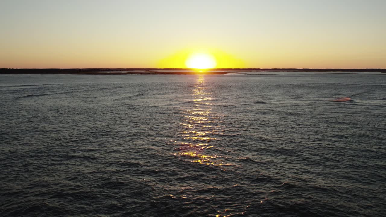 Aerial dolly to serene seascape with sunset beam ray of golden light crossing water, Chincoteague Island Virginia, slow motion