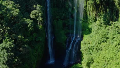 aerial dolly view of sekumpul waterfall surrounded by lush rainforest in bali, indonesia. cascading water through dense green jungle in a tropical paradise setting